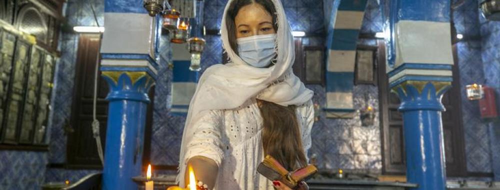 A woman lights a candle in a Tunisian synagogie