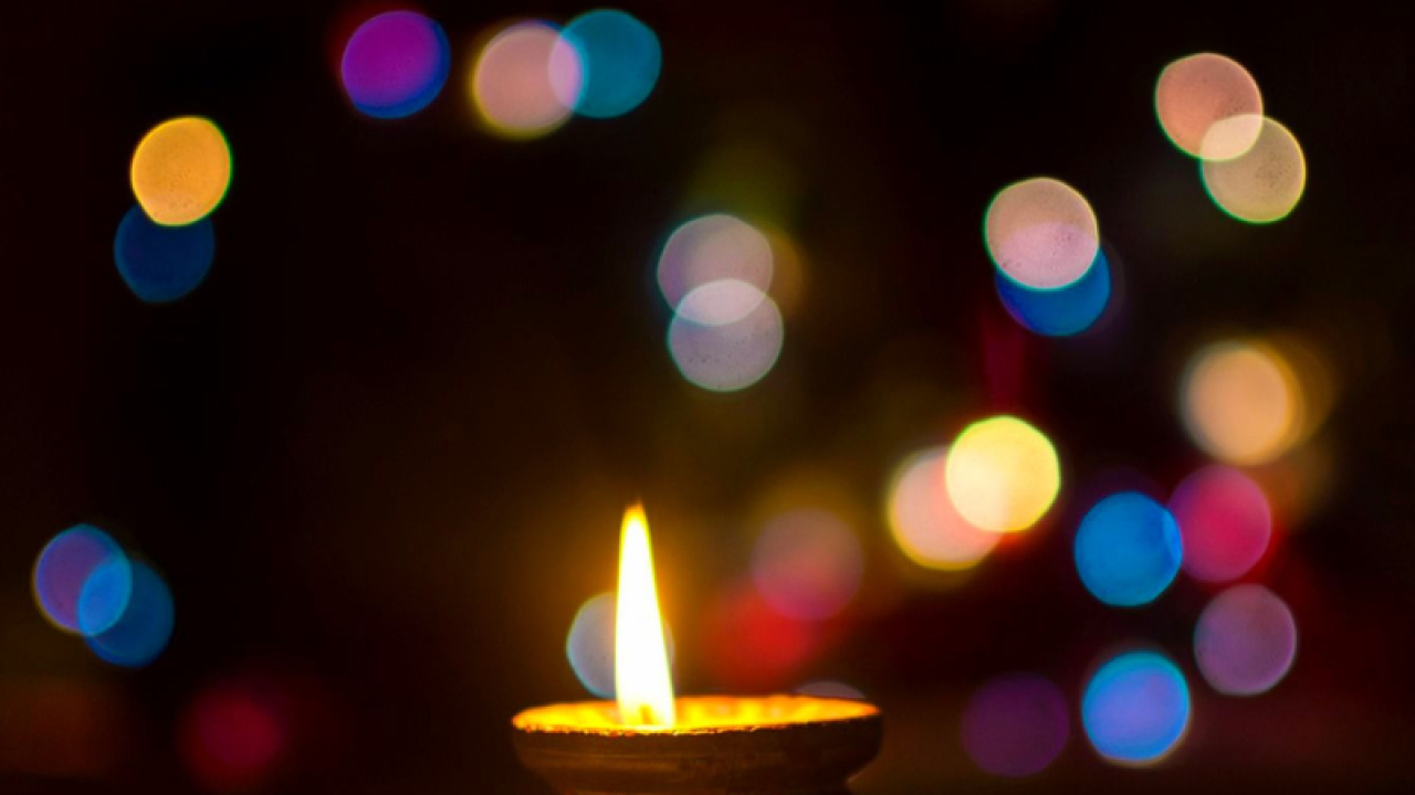 Soft colored lights on a dark background with a single lit candle