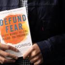 black hands holding a copy of the book "defund fear"